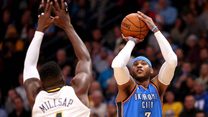 Paul Millsap trata de taponar el tiro de Carmelo Anthony, quien superó a Allen Iverson en la lista de anotadores históricos.