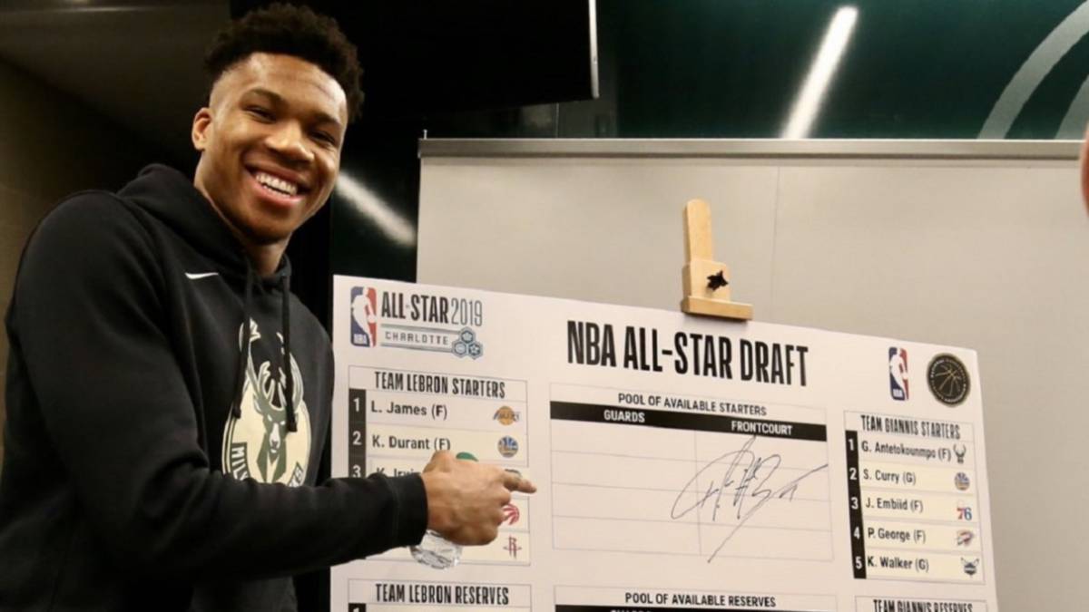 Giannis Antetokounmpo posa junto a la pizarra donde aparecen los equipos para el All Star Game 2019