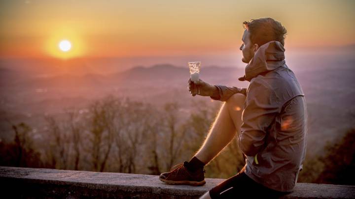 Runner mirando la puesta de sol con una cerveza en la mano