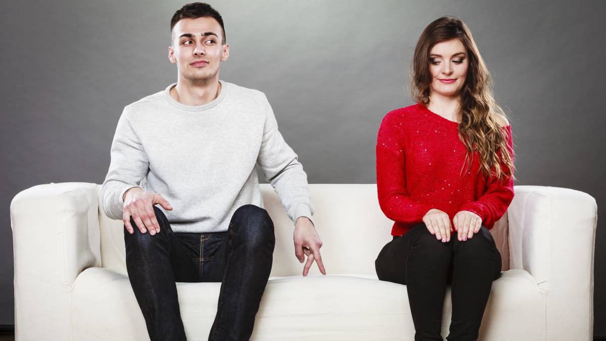 Chico y chica sentados en un sofá en actitud de flirteo