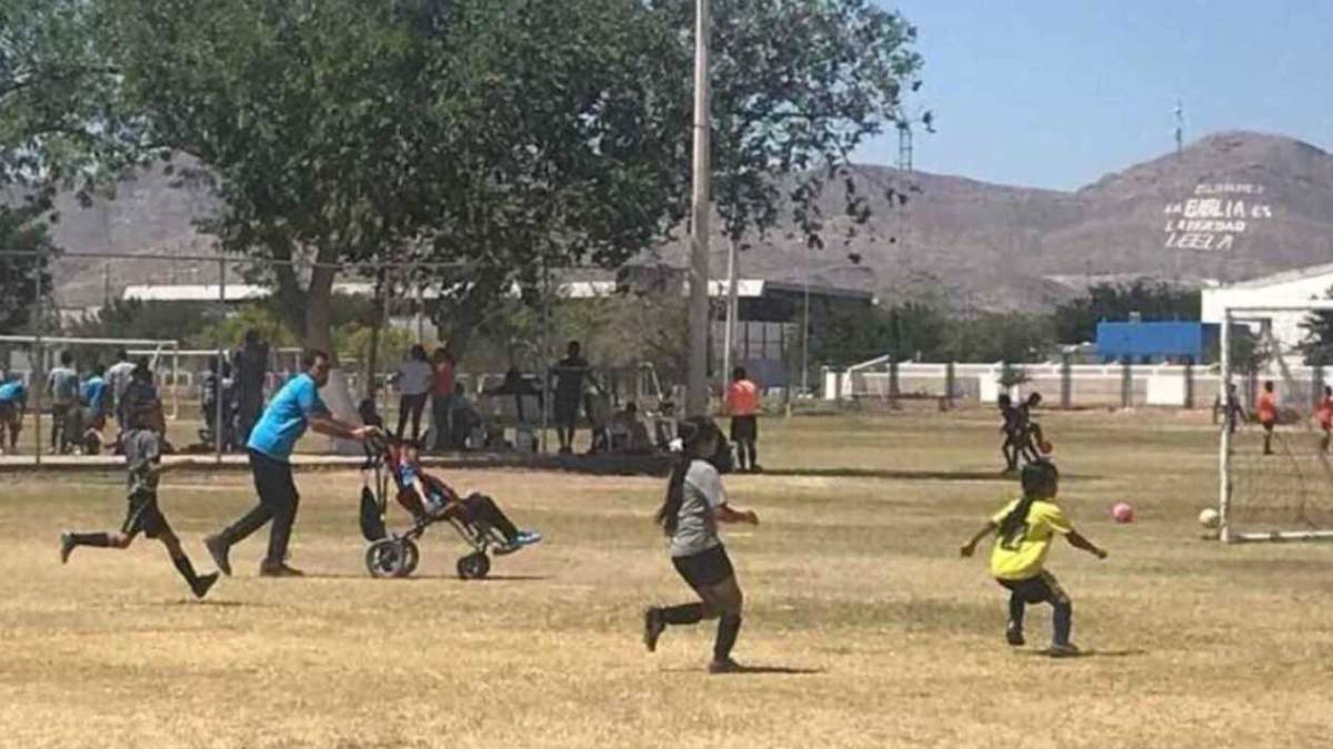 Papá empuja la silla de ruedas de su hijo para que pueda jugar fútbol