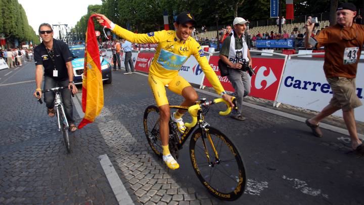 Alberto Contador, vestido de amarillo y llevando la bandera de España, celebra en los Campos Elíseos de París su título de campeón del Tour de Francia 2009.