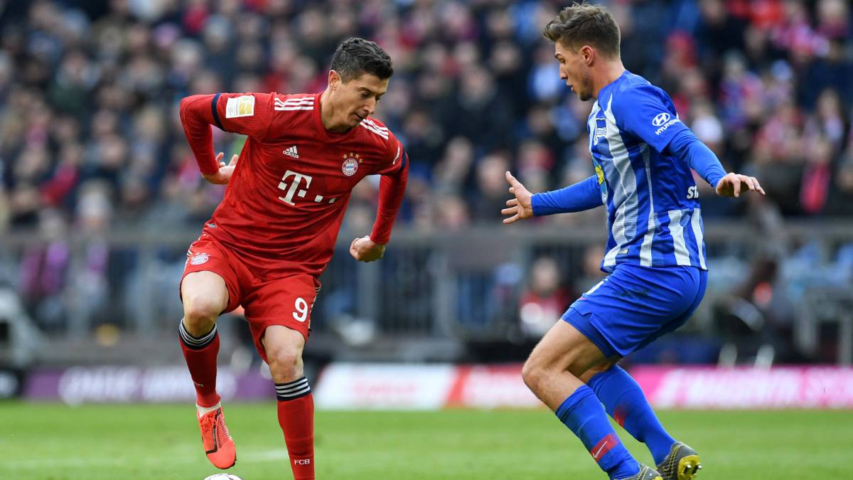 Lewandowski busca superar a un rival en el partido ante Hertha por la Bundesliga