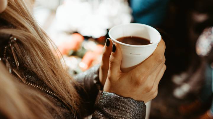 Una mujer se calienta con una taza de vino caliente.