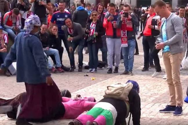 PSV fans throw money at beggars for a performance.
