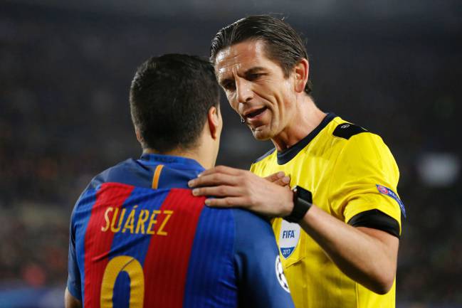 Referee puts hand on shoulder of Barcelona's Uruguayan forward Luis Suarez