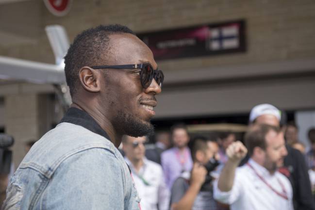 Olympic champion Usain Bolt of Jamaica takes a hot lap with Mercedes driver Lewis Hamilton.