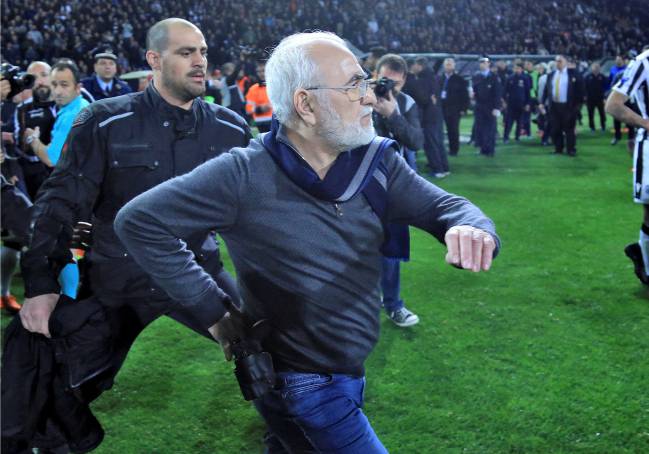 Russian-born Greek businessman and owner of PAOK Salonika, Ivan Savvides, pictured with what appears to be a gun in a holster, enters the pitch.