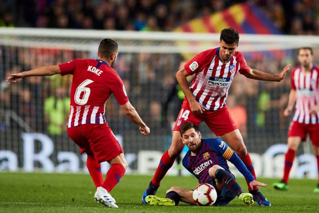 Barcelona's Lionel Messi battles with Atlético Madrid pair Rodrigo and Koke.
