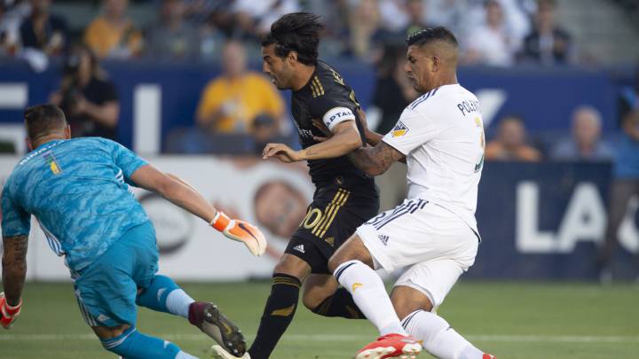 Carlos Vela moves the ball past LA Galaxy defender Diego Polenta in front of goalkeeper David Bingham during the first half at Dignity Health Sports Park.