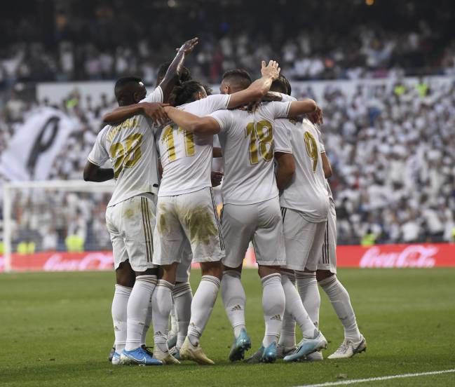 Looking good | Players surround Benzema after he gives Real Madrid the lead against Valladolid.