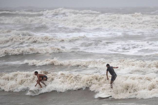 Local residents Alejandero Carcano, 16, and Jesse Garewal, 18, surf in high swells from Hurricane Hanna in Galveston, Texas, U.S., 25 July 2020.