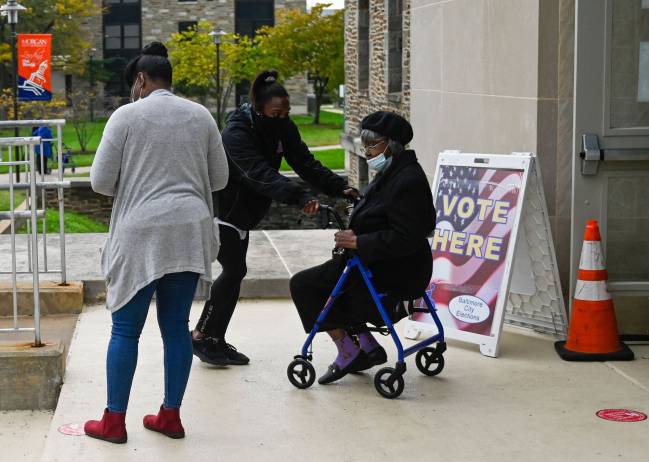 Every vote counts | A woman is helped into an auditorium at Morgan State University, Baltimore, to vote.
