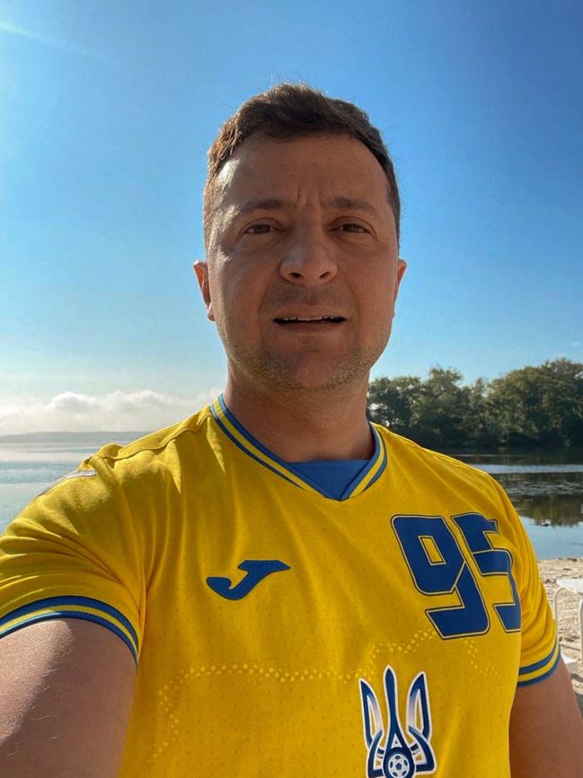 Ukrainian President Volodymyr Zelensky making a selfie wearing Ukraine's national football team shirt.