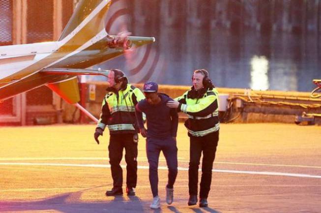 Los funcionarios del helipuerto, alejando a Demarai Gray de las hélices traseras del helicóptero.
