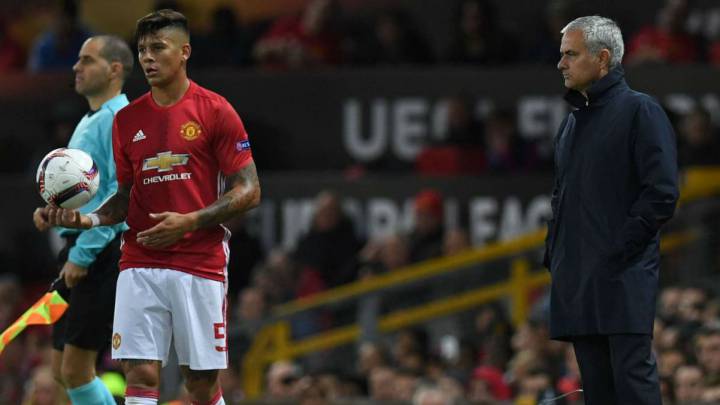 El defensa argentino Marcos Rojo se dispone a sacar de banda en presencia de su entrenador, el portugués Jose Mourinho, en un partido del Manchester United.