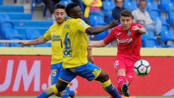 Los jugadores de Las Palmas, el delantero nigeriano Oghenekaro Etebo y el delantero Ignacio GIl, defienden ante el centrocampista del Getafe, Francisco Portillo.