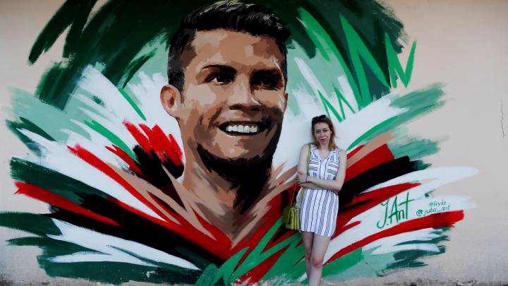 Turistas y aficionados se fotografían con un graffitti de Cristiano Ronaldo.