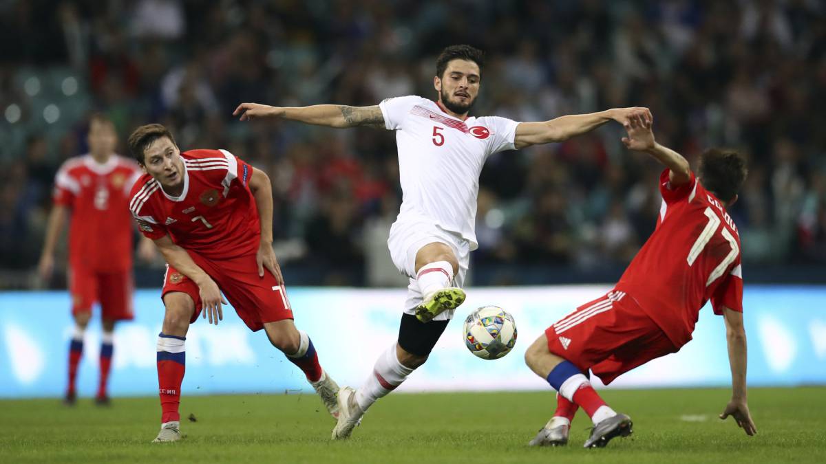 Okay Yokuslu se lanza a por un balón ante el jugador de la selección rusa Aleksandr Golovin.