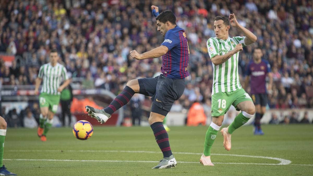 El delantero uruguayo del Barcelona Luis Suárez dispara a puerta ante la presión del centrocampista mexicano del Real Betis Andrés Guardado en el encuentro de LaLiga Santander.