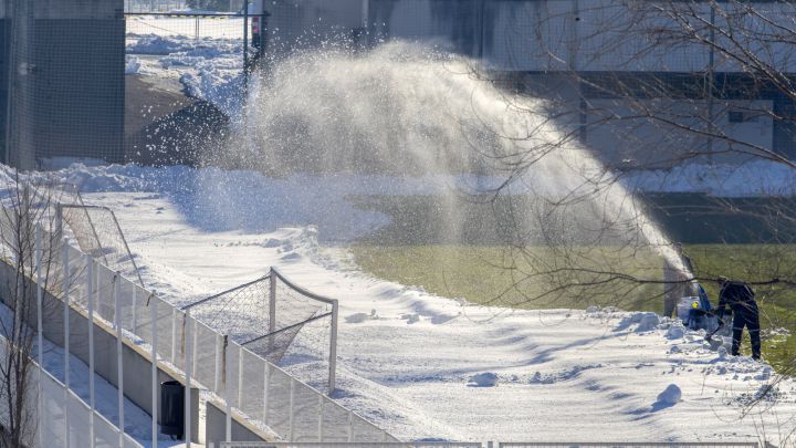 Operarios quitando nieve del césped de la Ciudad Deportiva.
