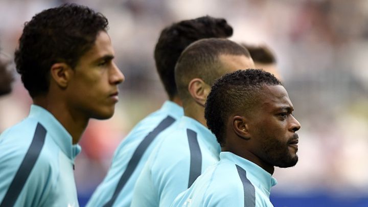 Raphael Varane y Patrice Evra calientan antes de un partido con la selección francesa.