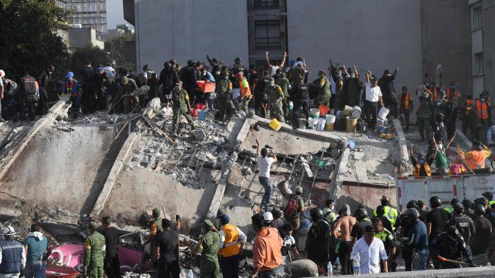 Cuerpos de emergencia y voluntarios ayudan en las labores de rescate de un edificio derrumbado por el sismo en México.
