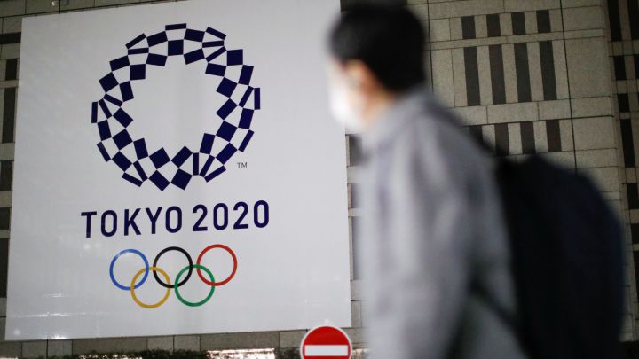 Un ciudadano con mascarilla pasa por delante de un cartel con el logo de los Juegos Olímpicos de Tokio 2020.