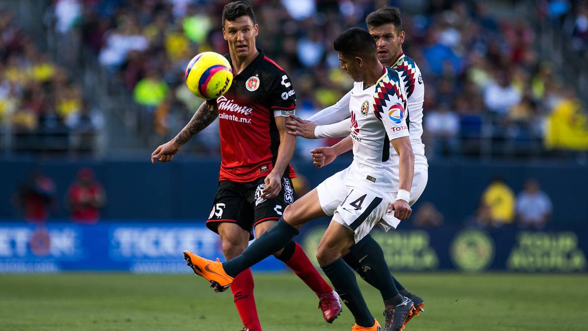 Joe Corona disputa un balón con un jugador de Xolos en partido amistoso.