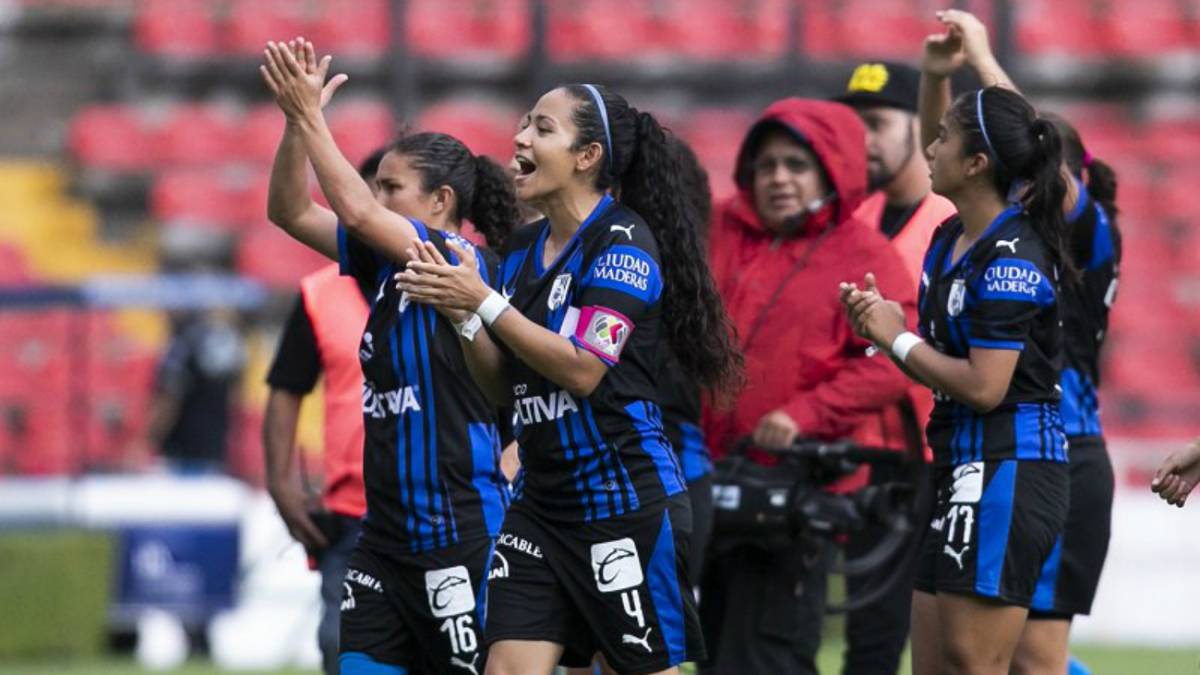 Jugadoras de fútbol vestidas con uniforme negro y azul, aplaudiendo