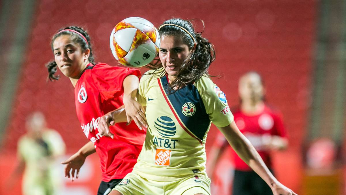 Jugadoras de futbol, una vestida con short amarillo y playera amarilla con azul, la otra viste short negro con playera roja