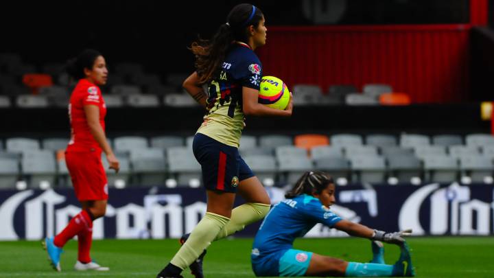 Jugadoras de fútbol en el campo de juego, dos caminan y una está en el cesped