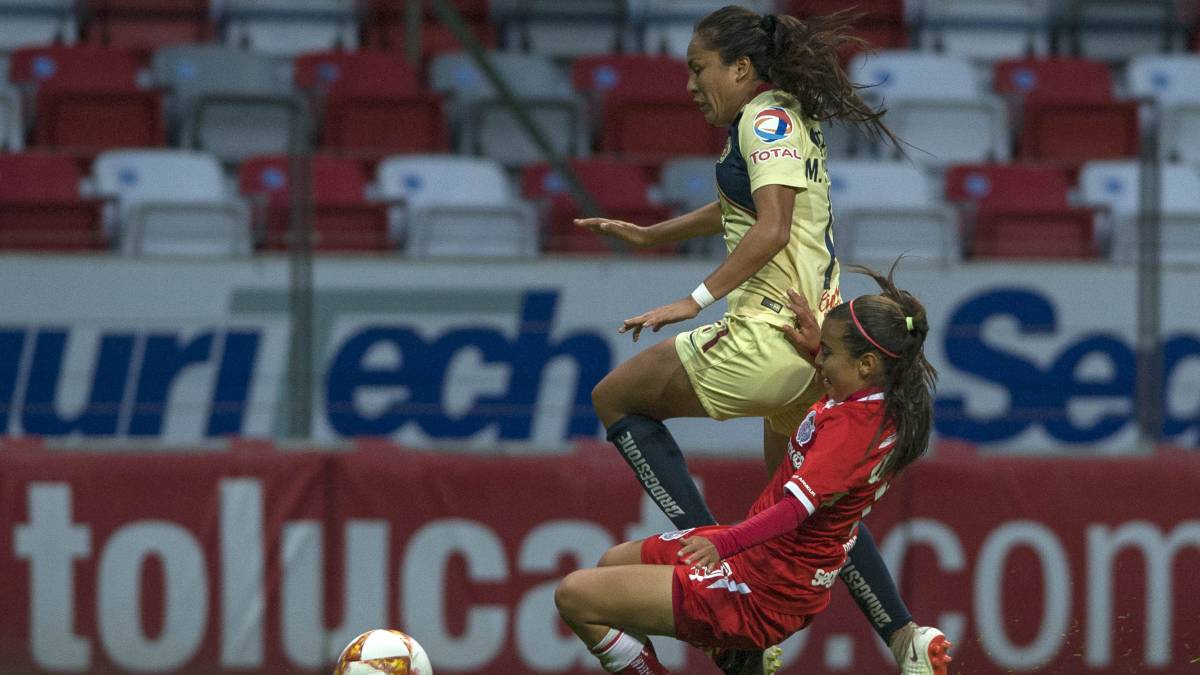 Jugadoras disputando el balón en el campo de juego, una viste uniforme amarillo y la otra uniforme rojo