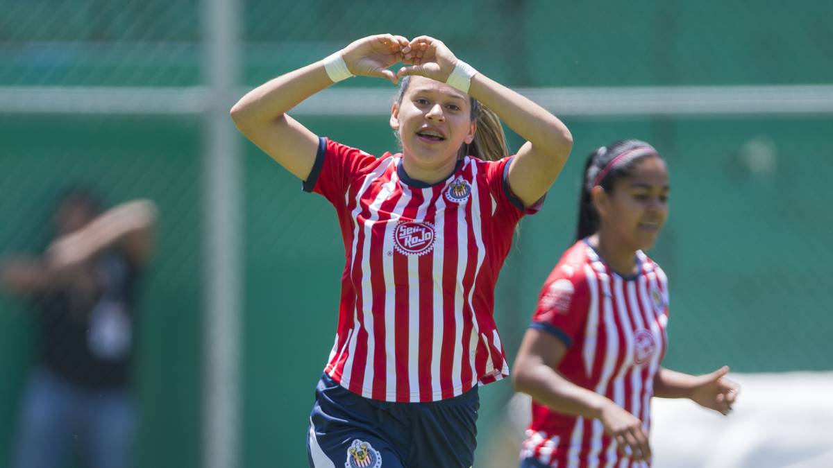 Jugadora de Fútbol corriendo por le campo de juego alzando las manos