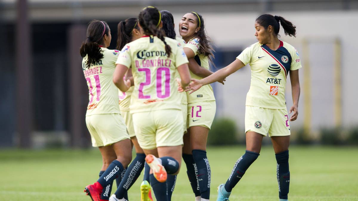 Jugadoras de fútbol abrazandoce en el campo de juego