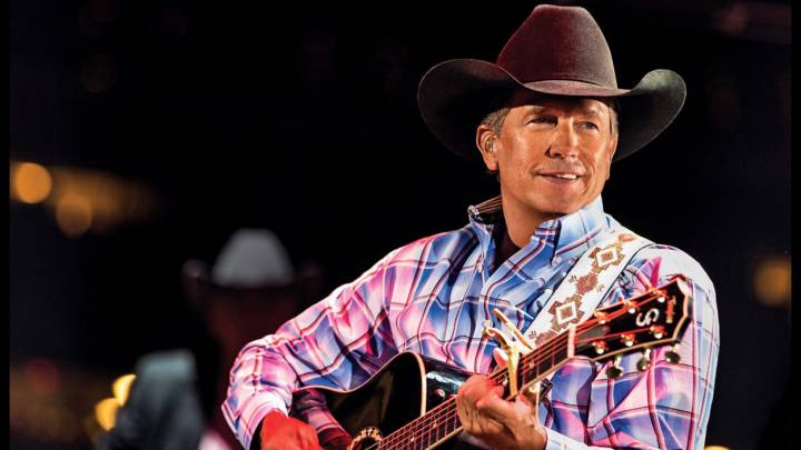 La estrella de country George Strait, quien estará presente en el Houston Rodeo, con una camisa a cuadros, toca la guitarra previo a un concierto