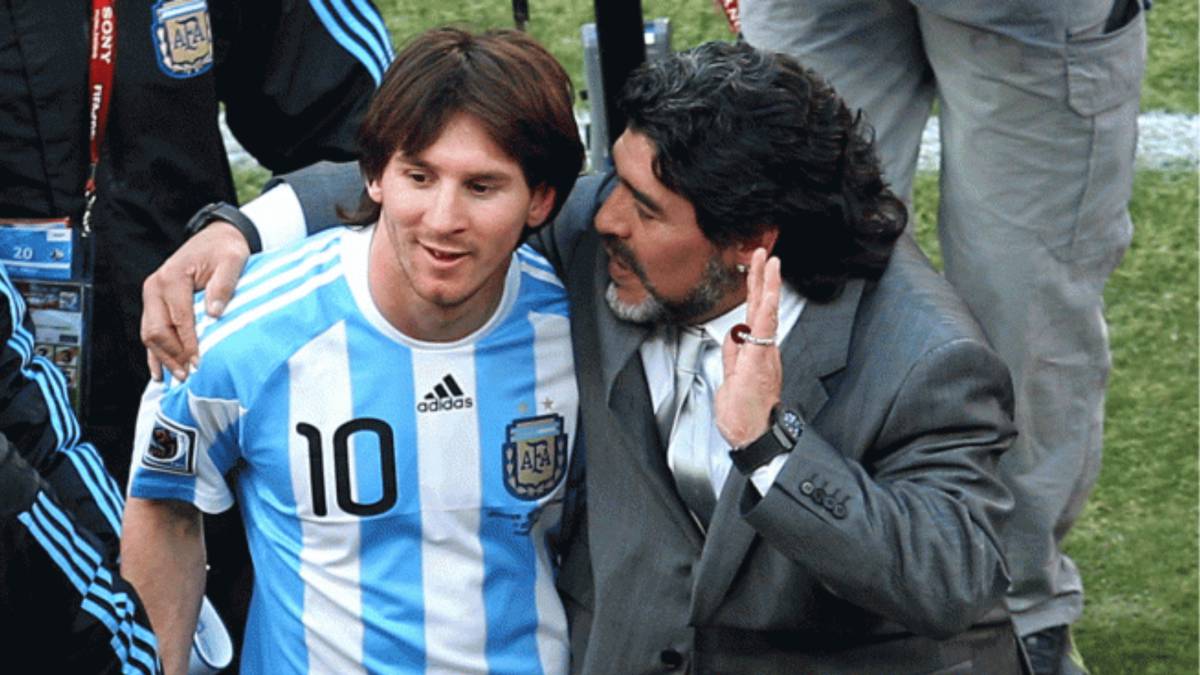 Lionel Messi y Diego Armando Maradona platican sobre una cancha.