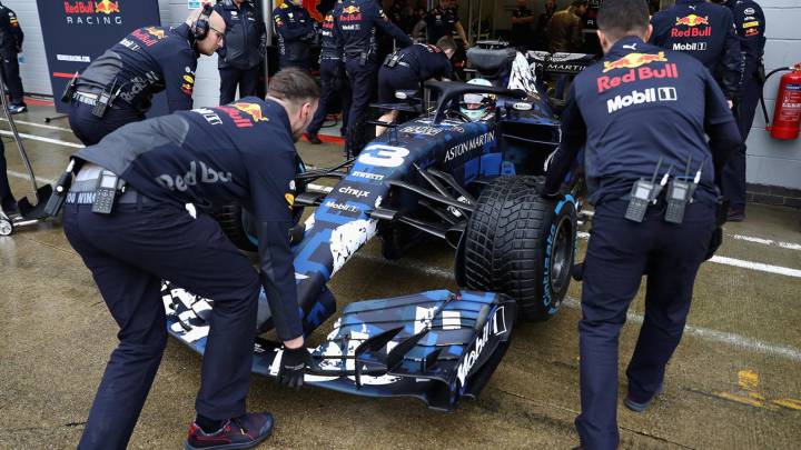 Los mecánicos de Red Bull empujan el coche de Ricciardo a boxes durante el filming day que hizo en Silverstone.