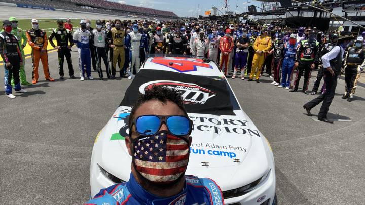 Bubba Wallace se fotografía junto al resto de pilotos de la Nascar delante de su coche.