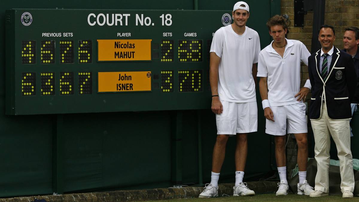John Isner y Nicolas Mahut posan junto al árbitro Mohamed Lahyani y el marcador tras su histórico partido en Wimbledon, en el que el estadounidense se impuso tras ganar el quinto set por 70-68.