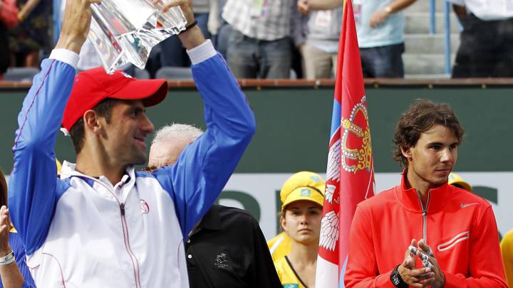 Novak Djokovic levante el título de campeón de Indian Wells de 2011 ante la mirada de Rafa Nadal, subcampeón de esa edición.