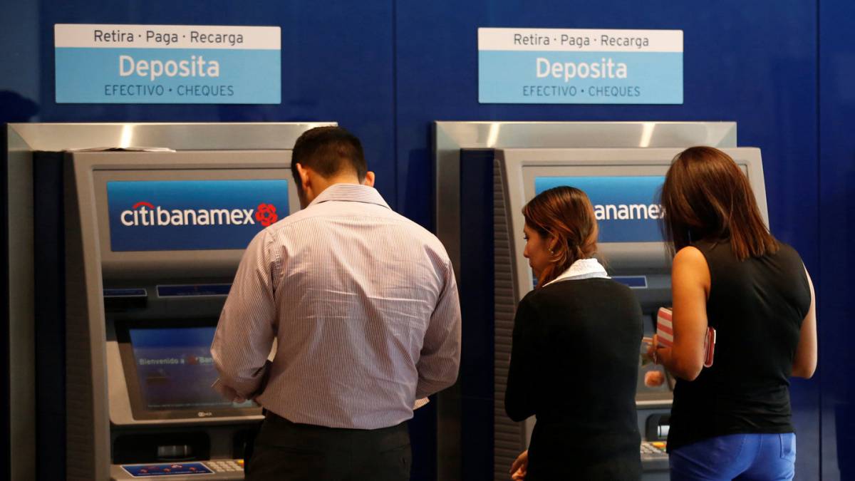 Varias personas sacan dinero de cajeros automáticos.