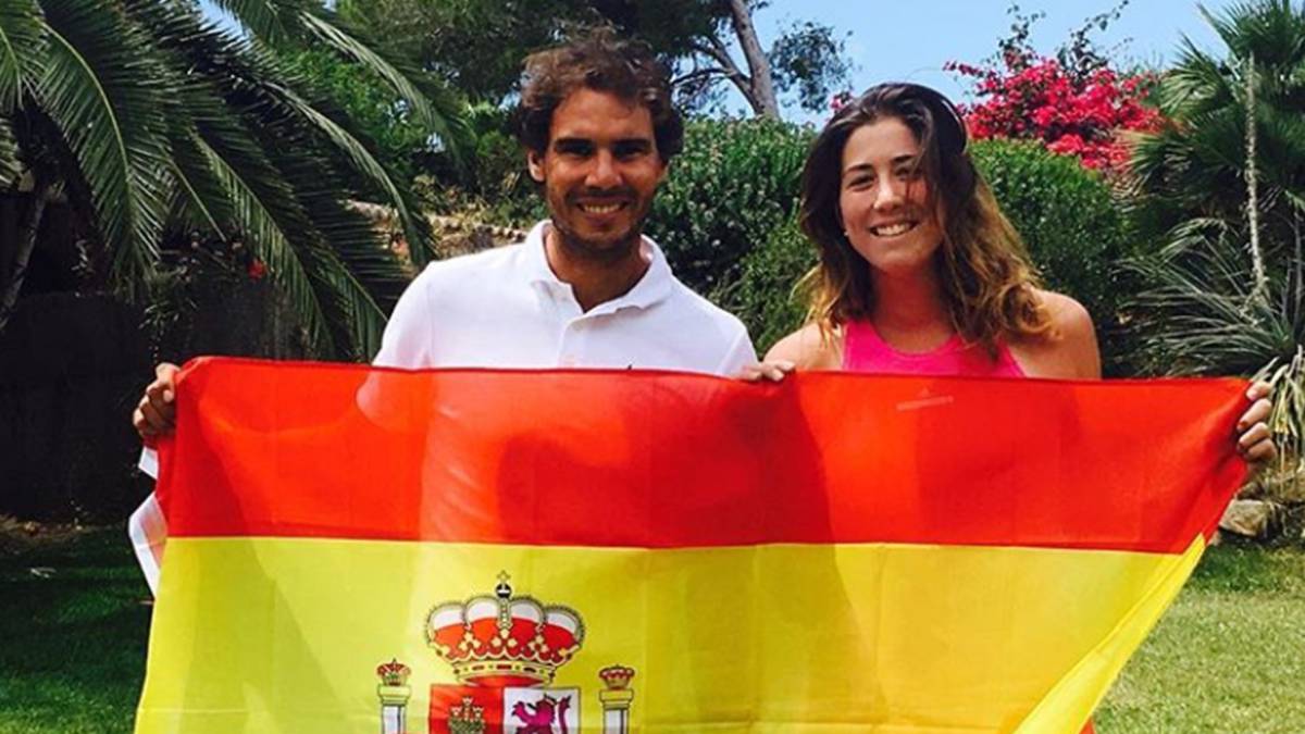 Los tenistas Rafa Nadal con Garbiñe Muguruza sujetando una bandera de España en un jardín. Foto Instagram @garbimuguruza