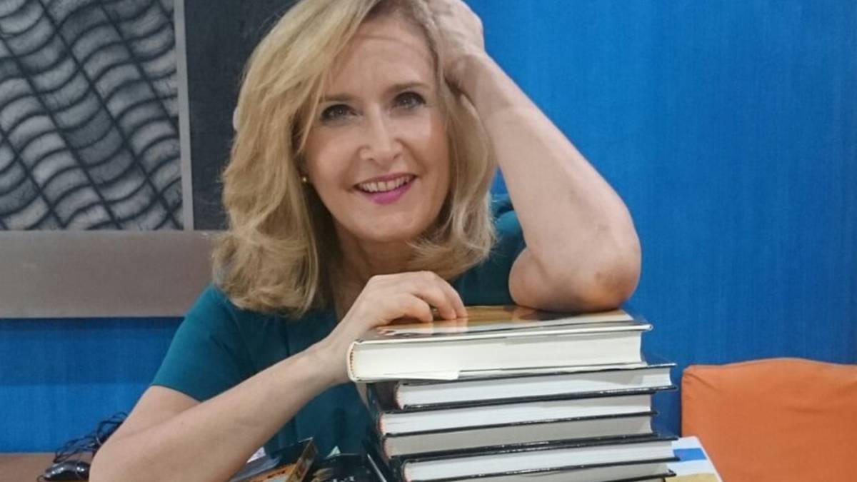 La periodista Nieves Herrero junto a una pila de libros.