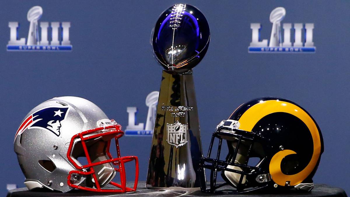 Trofeo Vince Lombardi con cascos de Patriots y Rams a los costados.