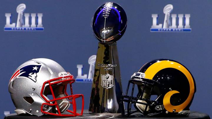 Trofeo Vince Lombardi con cascos de Patriots y Rams a los costados.