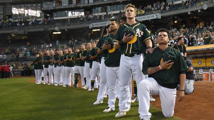Bruce Maxwell, con Mark Canha atrás, protesta durante el himno nacional