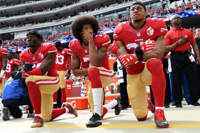 Colin Kaepernick (centro), hincado durante el himno estadounidense