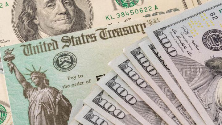 Cheque de estímulo de Estados Unidos y billetes de 100 dólares estadounidenses