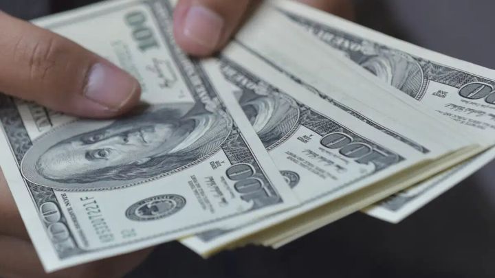 Mano sosteniendo billetes de 100 dólares estadounidenses